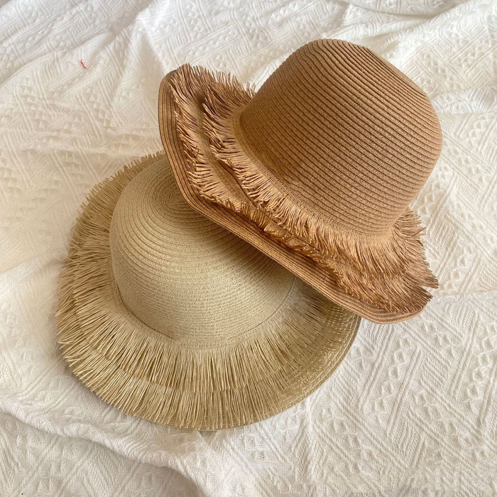 Two Fringed Designed Seaside Beach Straw Hats by Beachy Cover Ups on top of a bed.