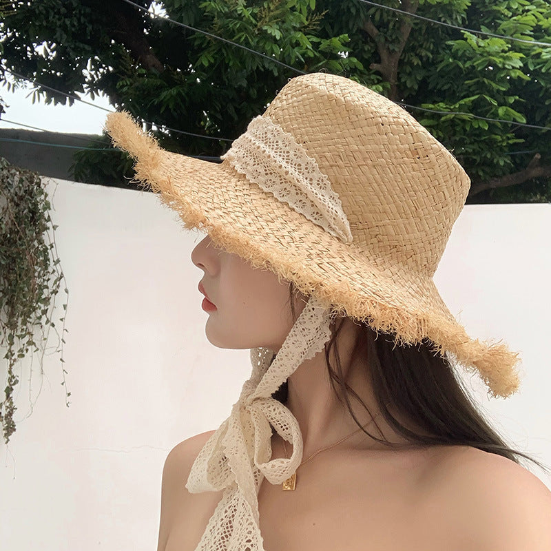 A woman wearing a Fringed Seaside Beach Lace Sun Hat by Beachy Cover Ups on the beach.