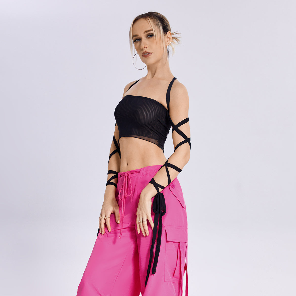 The model is wearing a fashion-forward Beachy Cover Ups Arm Ribbon Straps Black Top paired with pink cargo pants.
