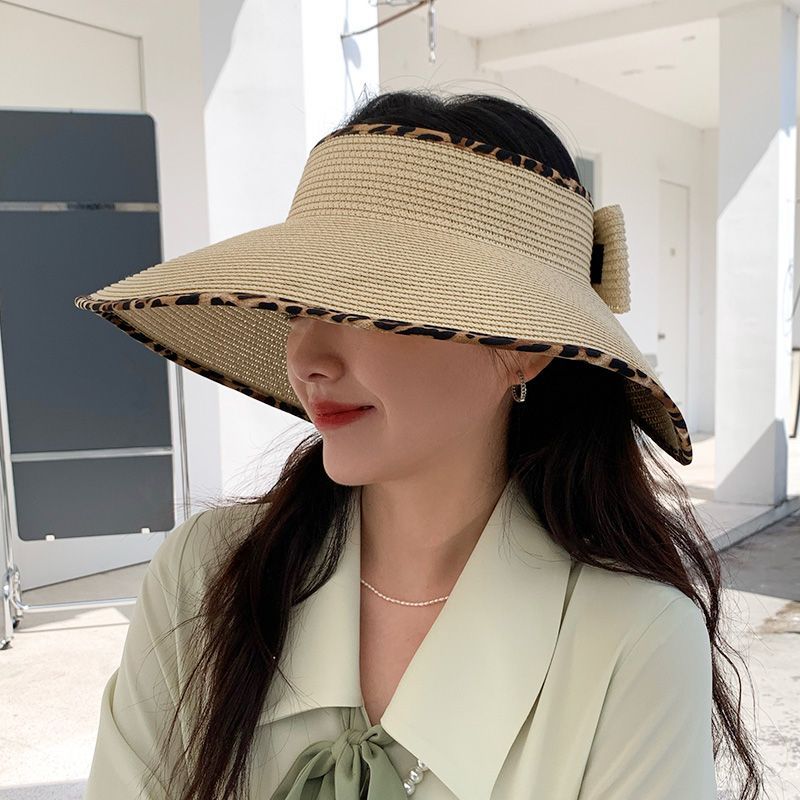 A woman wearing a Big Brim Cheetah Print Edge Straw Visor by Beachy Cover Ups.