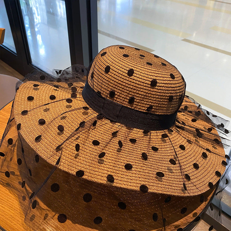 A Big Brim Lace Mesh Polka Dot Beach Hat with sun protection from Beachy Cover Ups sitting on top of a table.