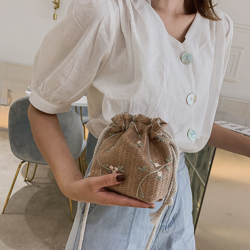 A woman is holding a Floral Lace Vacation Beach Bag from Beachy Cover Ups.