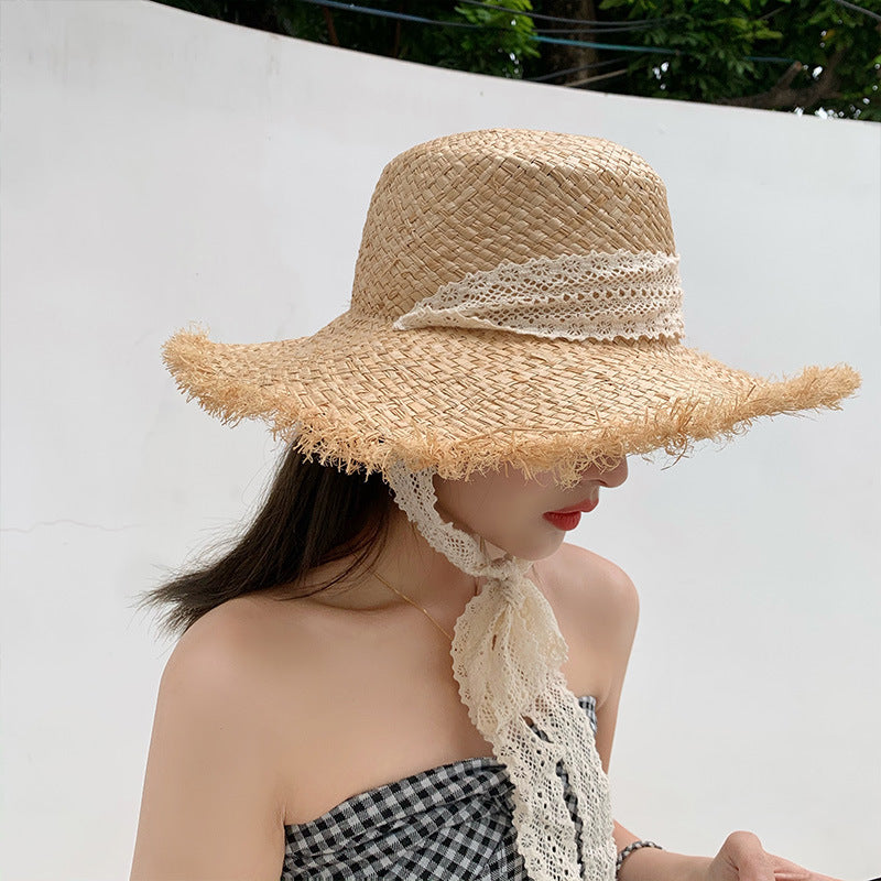 A woman wearing a Fringed Seaside Beach Lace Sun Hat from Beachy Cover Ups and a checkered scarf on the beach.