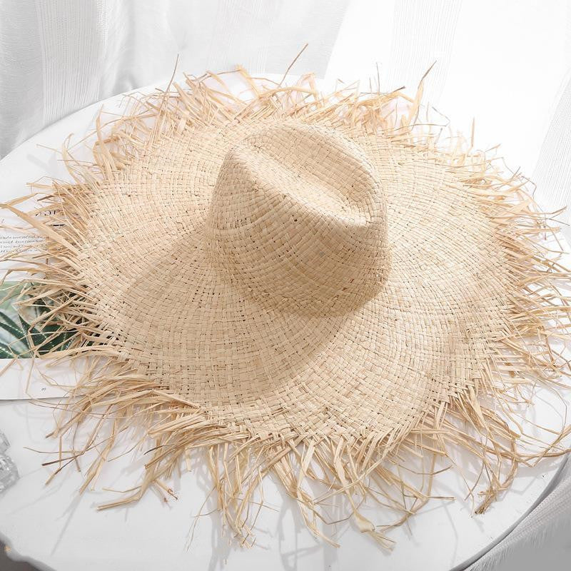 A Rustic Fringe Temperament Beach Hat by Beachy Cover Ups sitting on top of a table.