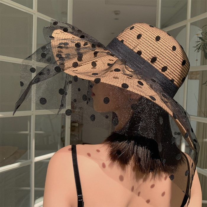 A woman donning a Big Brim Lace Mesh Polka Dot Beach Hat by Beachy Cover Ups for sun protection.