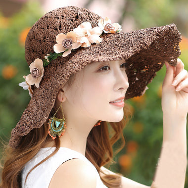 A woman wearing a Floral Foldable Big Brim Beach Straw Hat with floral patterns by Beachy Cover Ups.